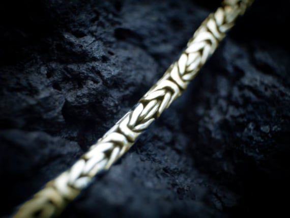 Närbild av ett bismarckhalsband i guld mot en mörk stenbakgrund.