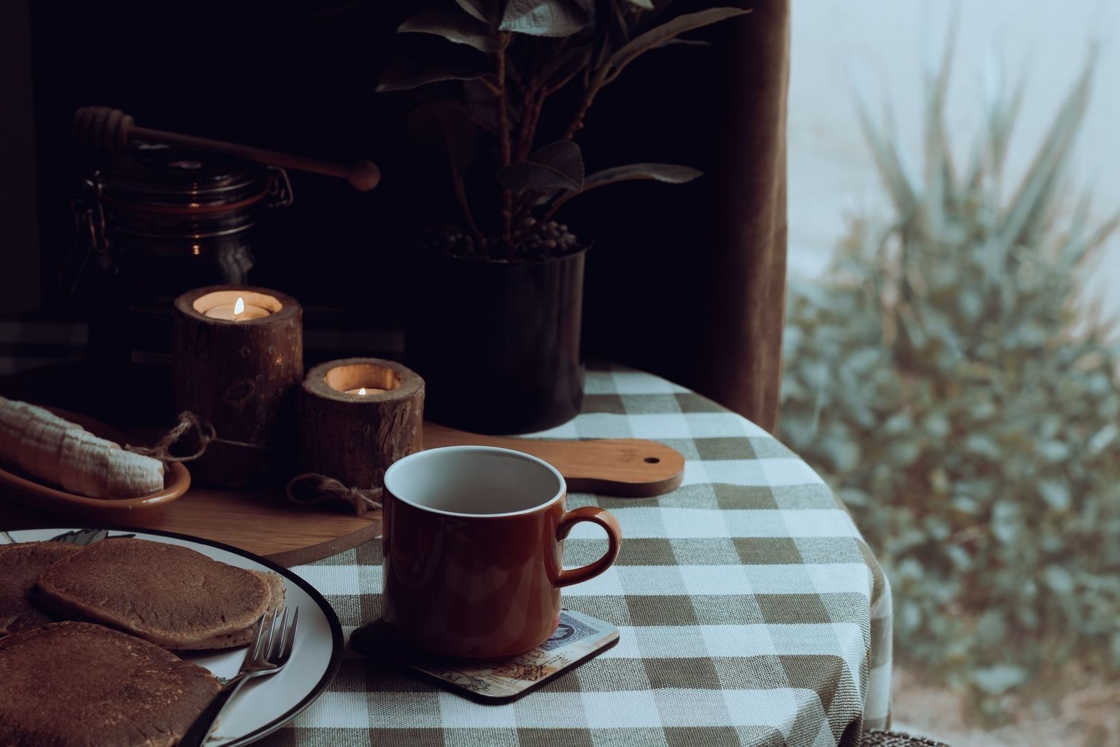 Mysig stund med kaffe, levande ljus och frukost vid ett fönster