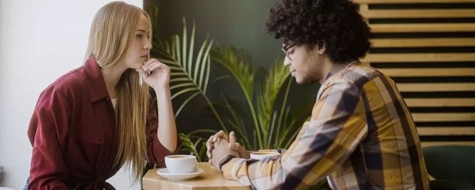 Två personer har ett allvarligt samtal över kaffe vid ett bord
