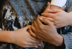 Flera händer med olika hudtoner hålls samman i en gemensam gest